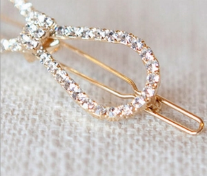 Close-up of a gold hair clip with sparkling rhinestones and elegant knot design
