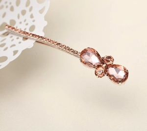 Nahaufnahme der roségoldenen Haarspange mit rosa Strass und Tropfenkristallen auf Spitze