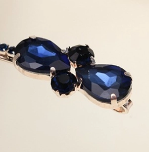 Detailansicht der tiefblauen Strasssteine in Birnenform mit goldener Krallenfassung