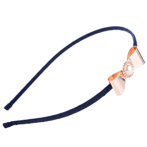 Détail d'un serre-tête en tissu bleu marine avec nœud en métal doré rose et perle