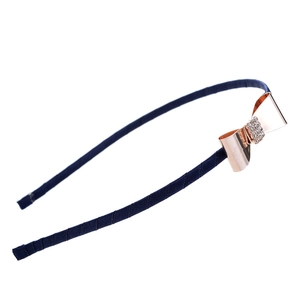 Détail d'un nœud en métal or rose avec strass sur un serre-tête en tissu bleu marine