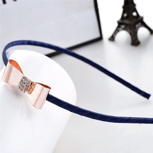 Détail d'un serre-tête en satin bleu marine avec un nœud en strass or rose