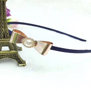 Détail d'un serre-tête bleu foncé avec un nœud en métal or rose et une perle