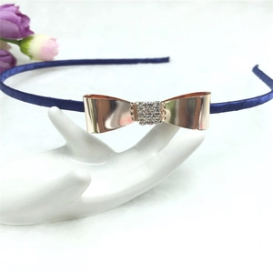 Détail d'un serre-tête en satin bleu avec nœud en métal or rose et cristaux brillants