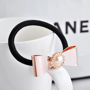 Détail de l'élastique à cheveux avec nœud en métal or rose et perle blanche
