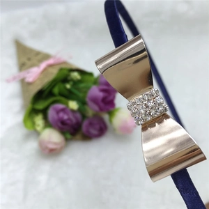 Détail d'un serre-tête en satin bleu avec un nœud en métal doré et des strass brillants