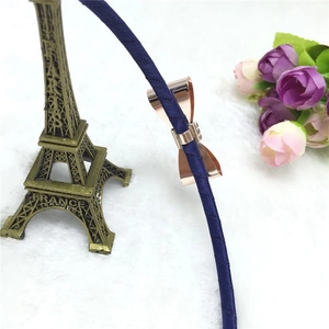 Détail du serre-tête en soie bleu marine orné d'un nœud décoratif en métal or rose