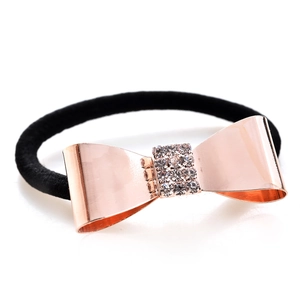 Détail de l'élastique à cheveux avec nœud doré rose et strass sur bandeau noir