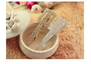 Detailed view of rectangular rhinestone hair clips in gold and silver set on plush fabric
