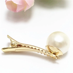 Detail van een elegante gouden haarspeld met een grote witte parel op een witte achtergrond