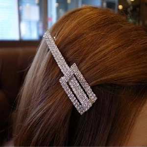 Close-up of sparkling rhinestone rectangular hair clip worn on long brown hair