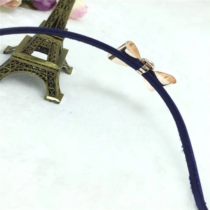 Détail d'un serre-tête en tissu bleu marine avec nœud en métal doré et strass brillants