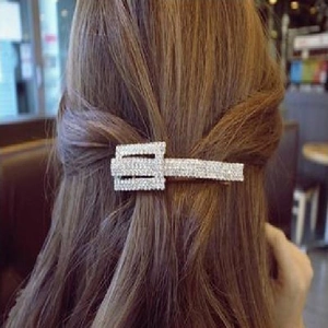 Detailed view of a silver rectangle hair clip with shimmering rhinestones worn on long hair