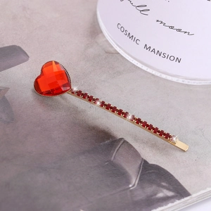 Detailed shot of vintage gold hairpin with red heart-shaped gemstone and crystal rhinestones