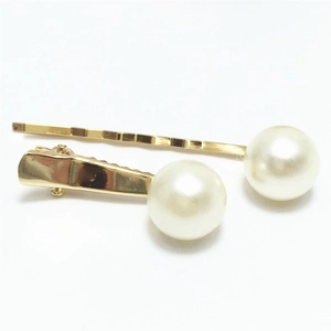 Detail van twee gouden haarspelden met witte imitatieparels op een witte achtergrond
