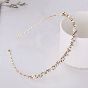 Elegant gold wavy headband decorated with sparkling rhinestones and white pearls.