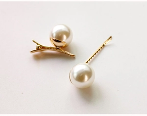 Detail van elegante gouden haarklemmen met glanzende grote parels op witte achtergrond