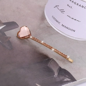 Detail of a pink heart-shaped crystal hair clip with gold alloy and small rhinestones