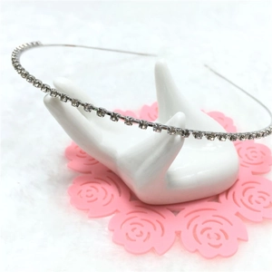 Close-up of thin silver headband with small clear rhinestones on a white hand display