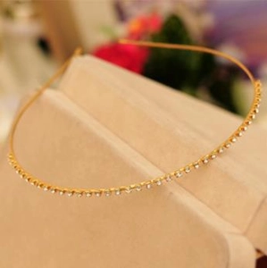 Detailed macro view of a thin gold headband featuring a single row of sparkling white rhinestones