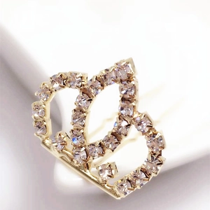 Detailed close-up of a gold-plated bridal crown hair pin with sparkling clear rhinestones