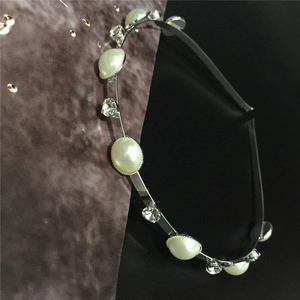 Détail d'un serre-tête fin en métal argenté orné de perles et de strass brillants
