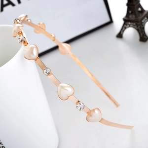 Rose gold heart pearl and rhinestone thin headband on a white ceramic cup