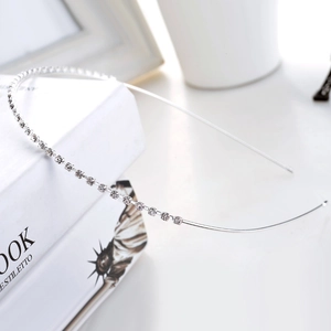 Elegant thin silver headband with single row of sparkling rhinestones on white books