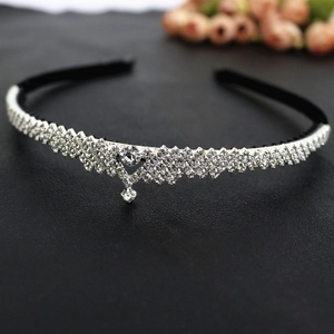 Détail d'un serre-tête couronne en strass étincelants avec pointe en V et cristal suspendu