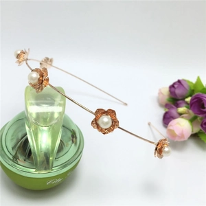 Détail d'un serre-tête fleurs or rose avec perles blanches sur armature métallique fine