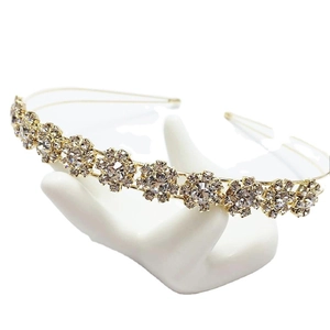Elegant gold headband with rhinestone sunflower designs displayed on a white hand stand