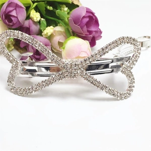 Détail d'une barrette à cheveux en forme de nœud argenté ornée de strass et pince à ressort