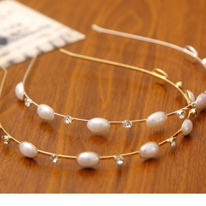 Eleganter goldener Haarreif mit weißen Perlen und Strass auf Holzoberfläche