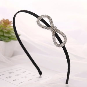 Elegant black headband with infinity rhinestone bow design on soft white mesh background