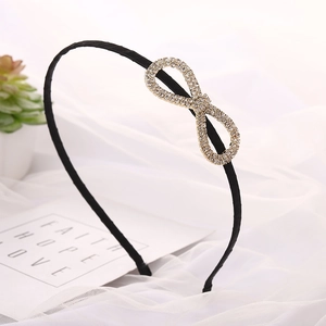 Elegant black headband with rhinestone infinity bow on soft white fabric background