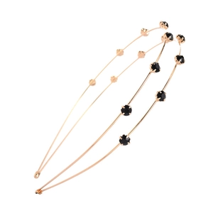 Detail view of a dual-layer golden metal headband featuring black faceted crystal rhinestones