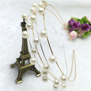 Dettaglio di eleganti cerchietti di perle in oro e argento su supporto decorativo