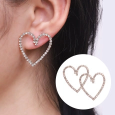 Close-up of elegant heart-shaped earrings with sparkling rhinestones on model