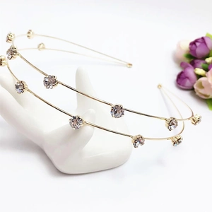 Elegant gold double-layered rhinestone headband with clear crystals on a white stand