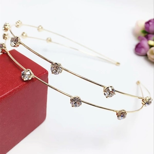 Detail view of two gold crystal headbands featuring round rhinestones on a red jewelry box