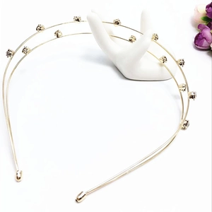 Detail of double-layer gold headband with sparkling crystals on a white jewelry stand
