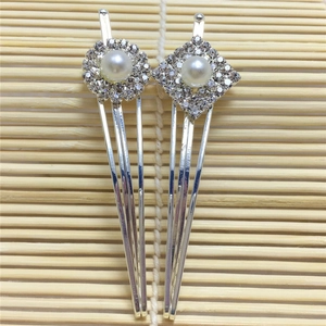 Détail de barrettes argentées en V ornées de strass étincelants et de perles blanches