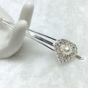 Barrette argentée avec cœur en strass et perle blanche sur fond en peluche