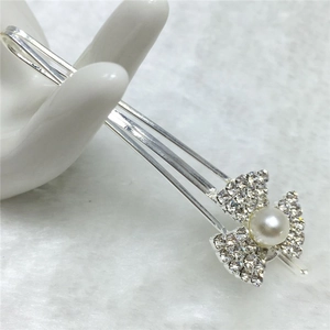 Détail d'une élégante pince à cheveux argentée avec strass et perle blanche sur une main