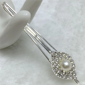 Gros plan d'une barrette argentée avec strass et perle sur fond de marbre chic
