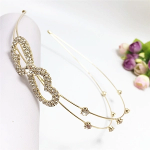Detailed close-up of a double-layered golden headband with rhinestone bow detailing