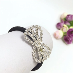 Detailed macro view of black elastic hair tie with sparkling rhinestone bow embellishment