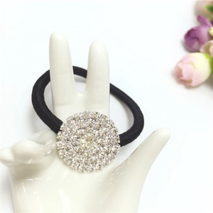 Detail view of a black elastic hair tie with a sparkling rhinestone flower ornament