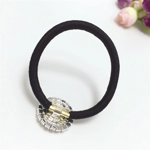 Detail of a black elastic hair tie with a luxury rhinestone circle and gold metal accent