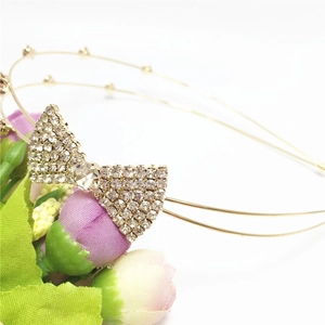 Détail d'un serre-tête doré à double rangée orné d'un nœud brillant en strass